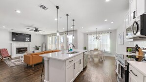 A modern kitchen with white cabinetry, a central island, and a dining area with a chandelier.