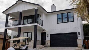 A two-story house with a balcony, a garage, and a golf cart in the driveway.