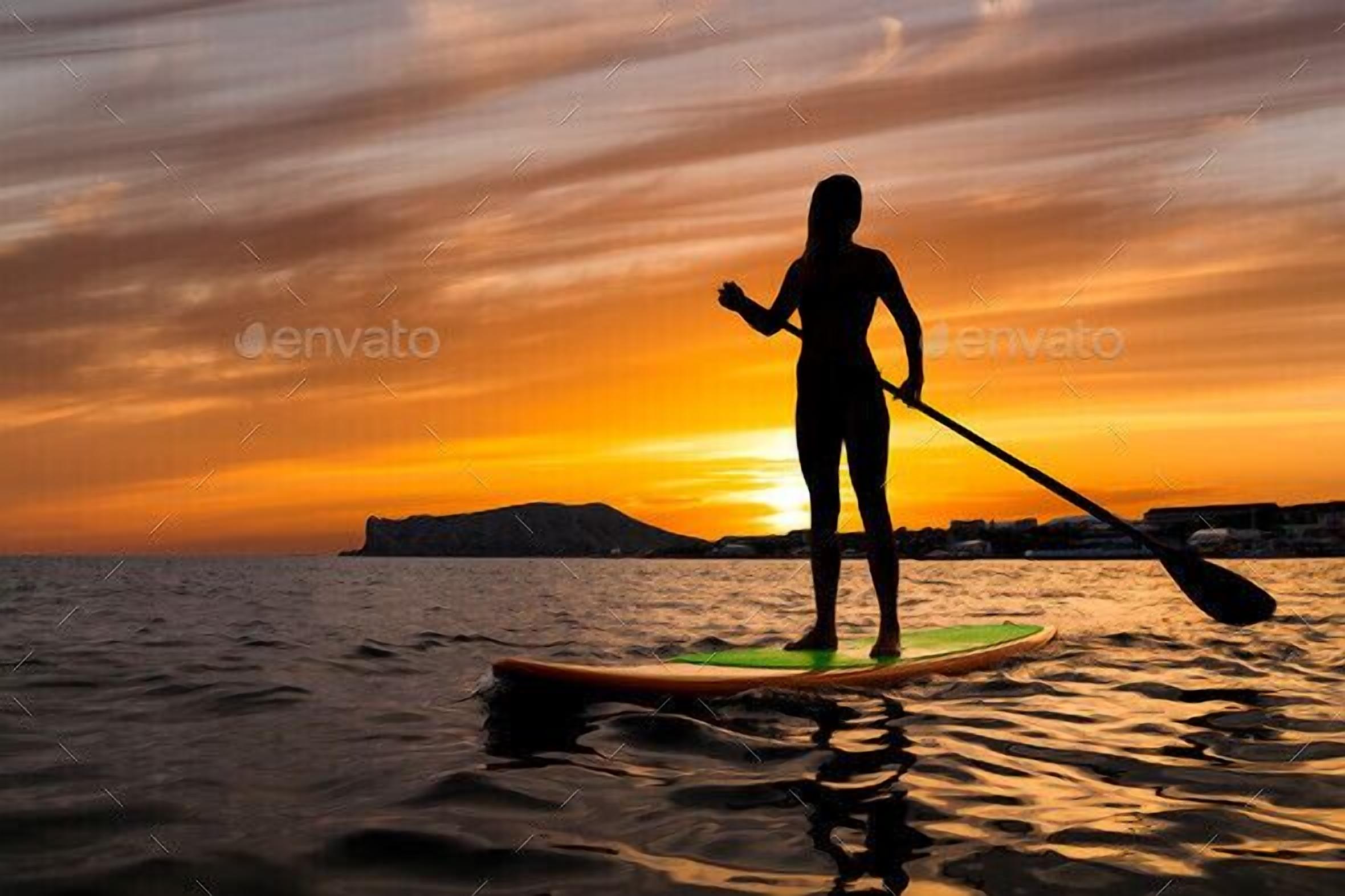 Silueta de una persona haciendo paddleboard al atardecer, con un sol poniente y formas de terreno lejano al fondo.