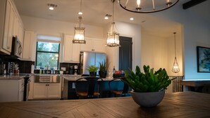 Une cuisine moderne avec des armoires blanches, un plan de travail en bois et des luminaires suspendus.