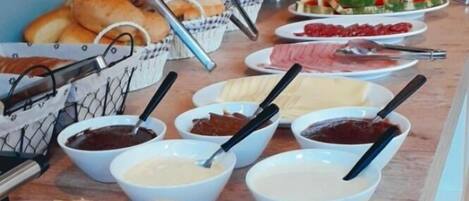 A buffet table with various food items including bread, dips, and sliced meats.