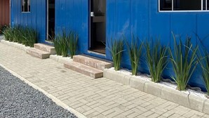 Une maison moderne avec une façade bleue, un toit en bois et une salle de bain visible de l’extérieur.