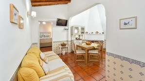 A cozy living room with a sofa, a dining table, and a kitchen area visible through an archway.