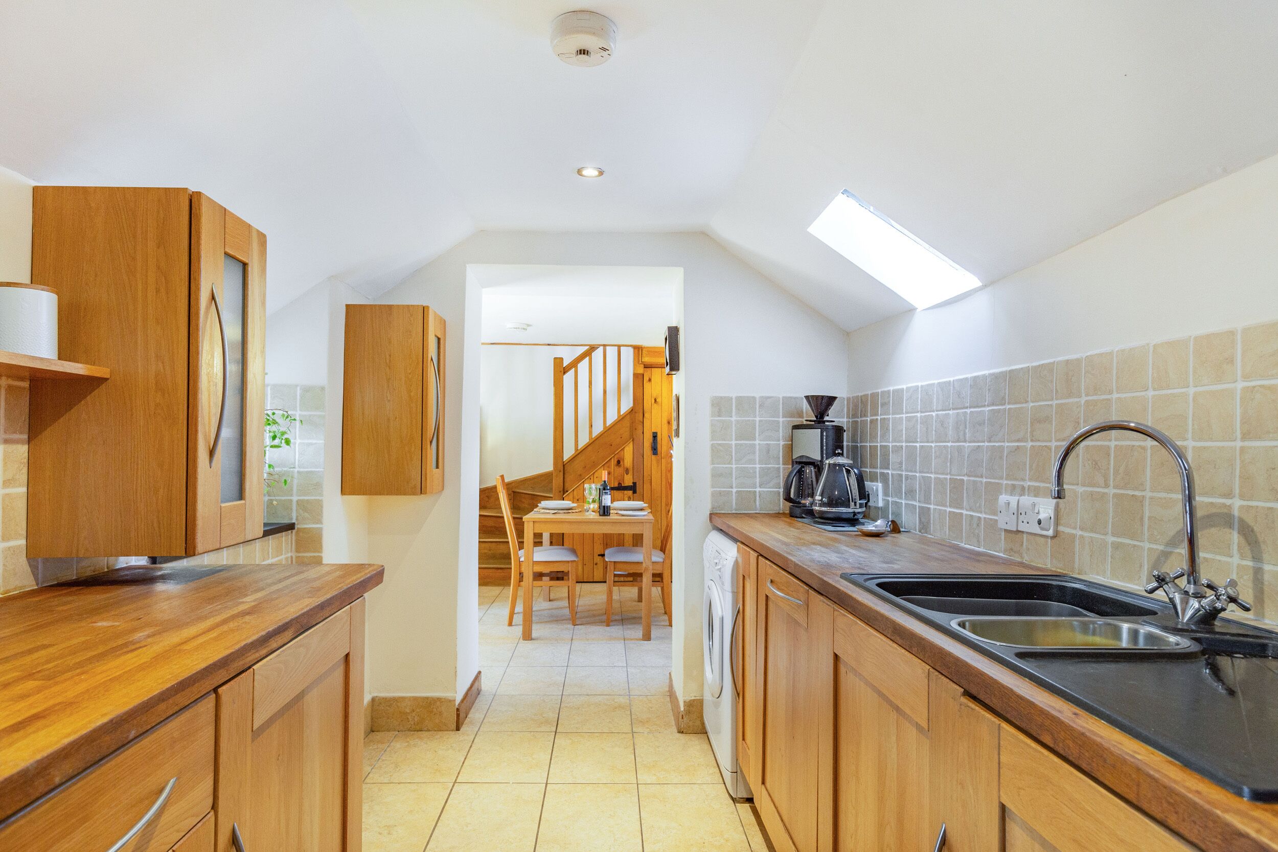 A kitchen with wooden cabinets, a sink, and a washing machine.