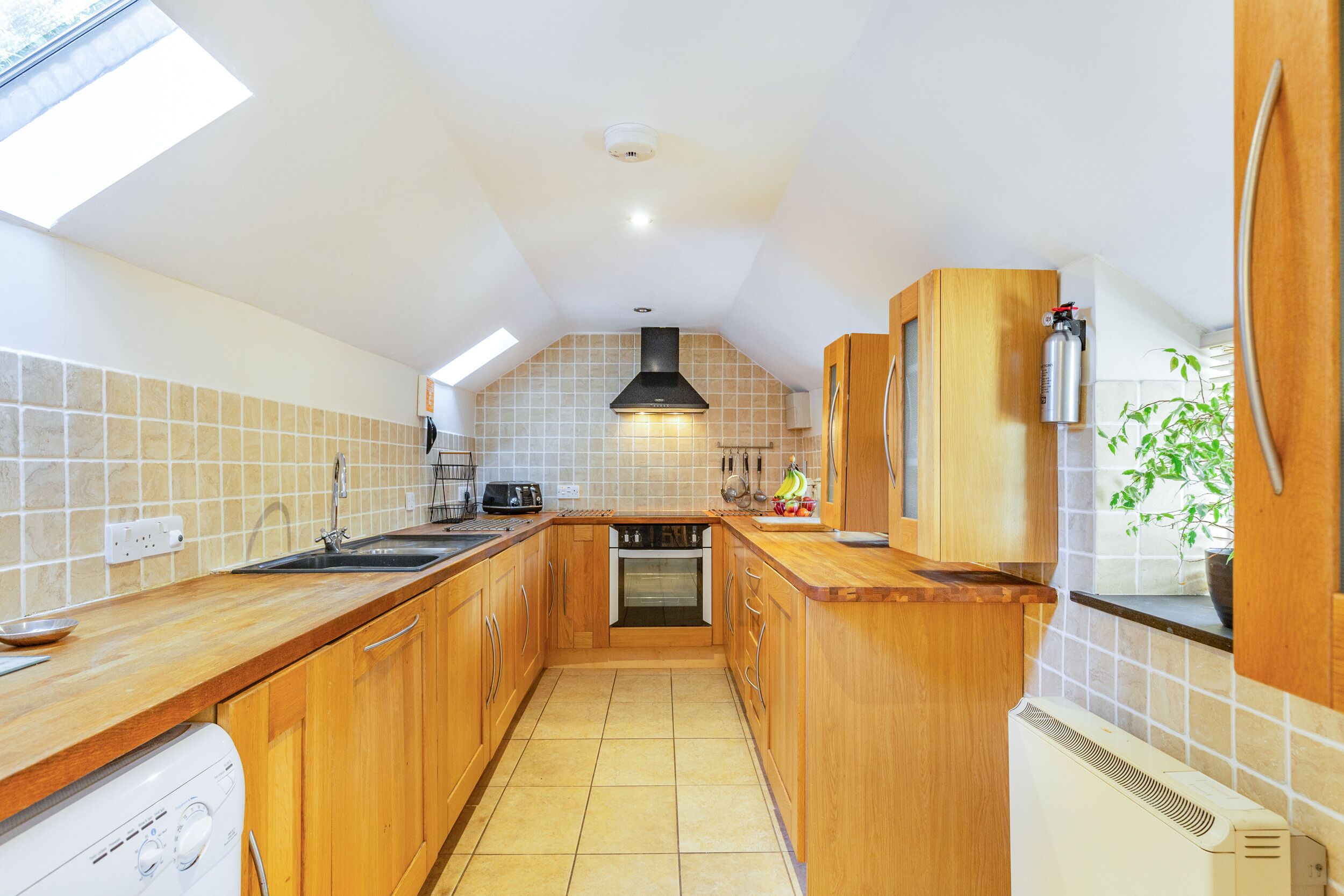 A kitchen with wooden cabinets, a built-in oven, a dishwasher, and a window above the sink.