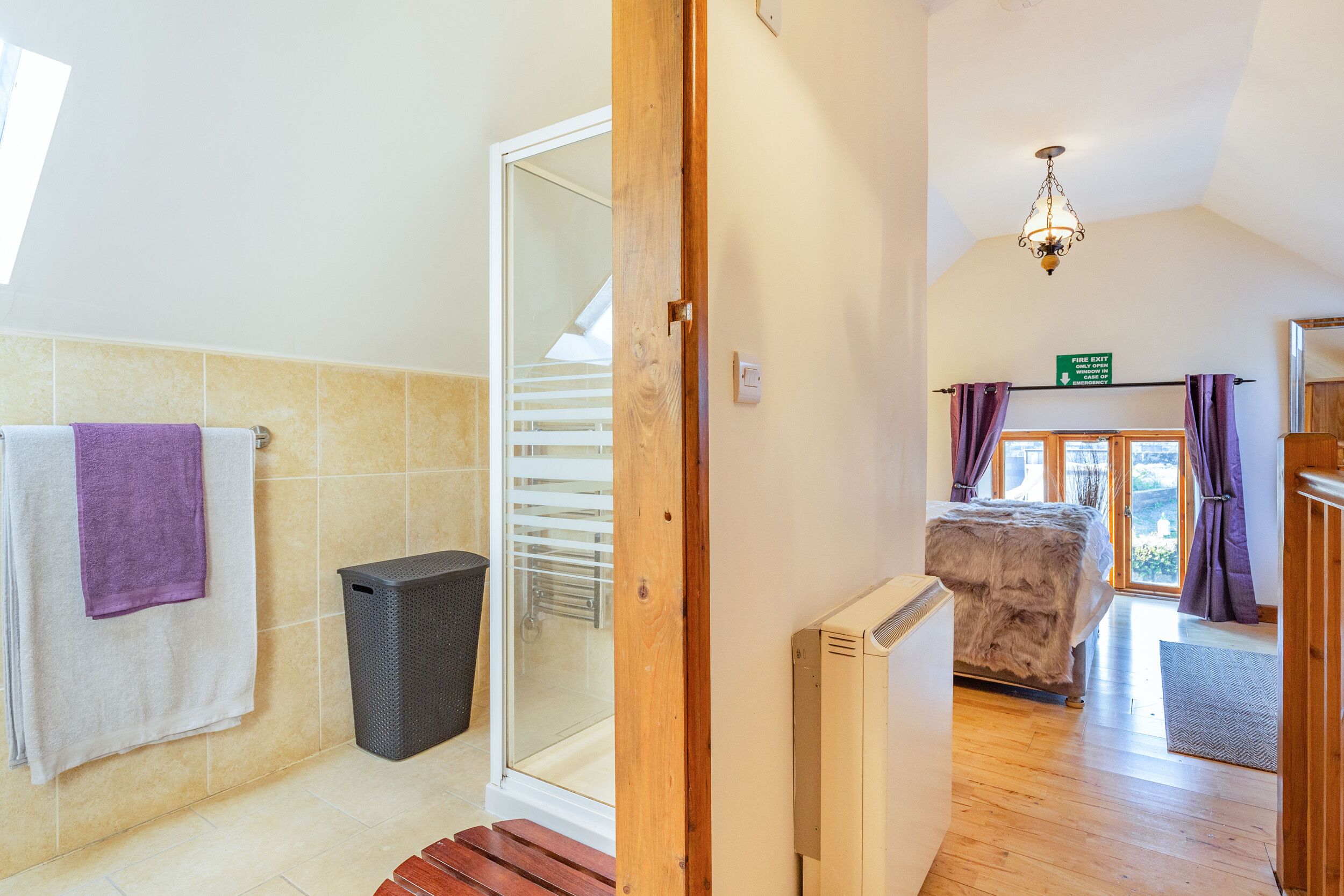Une salle de bain équipée d’un porte-serviettes, d’une poubelle et d’une cabine de douche en verre.