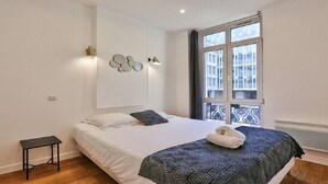 A bedroom with a bed, a small table, a window with a view, and wall-mounted lights. - Palais Royal – Musée du Louvre (line 1 and line 7), Pyramides & Bourse (line 3). (Paris)