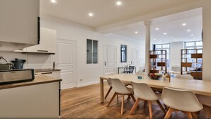 A modern kitchen with a wooden countertop, white cabinets, and a dining area with a long table and chairs. - Palais Royal – Musée du Louvre (line 1 and line 7), Pyramides & Bourse (line 3). (Paris)