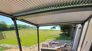 A hot tub under a covered patio with a view of a grassy yard and outdoor furniture. - 6/8 person gîte with swimming pool and jacuzzi (Thésée)