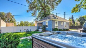A backyard with a hot tub, a house, and a well-maintained lawn.