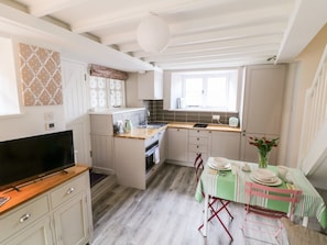 Cocina compacta con comedor, con encimera de madera, horno integrado y mesa de comedor para cuatro.