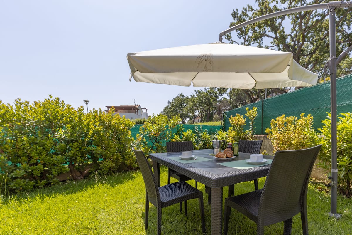 Un espace extérieur am énagé pour les repas, avec une table, des chaises et un grand parasol.
