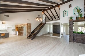 Stunning interior with exposed beams, stone fireplace, and artwork adorns this spacious room.