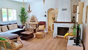 A cozy living room with a sofa, armchairs, a wooden coffee table, a fireplace, and a bookshelf with decorative items. - A Casa da Lagoa (Lagoa de Albufeira) - 800 da Praia (Sesimbra)