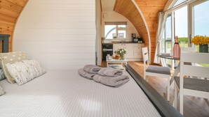 Un intérieur chaleureux et rustique, avec un lit, un coin repas et une cuisine.