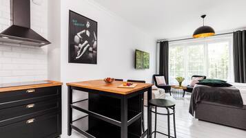Una cucina moderna con mobili neri, un piano di lavoro in legno e un piano cottura integrato. C'è un'area pranzo con un tavolo e sedie, e un'ampia finestra con tende.