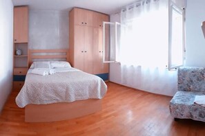 Une chambre à coucher avec un lit, une armoire, une chaise et une fenêtre.