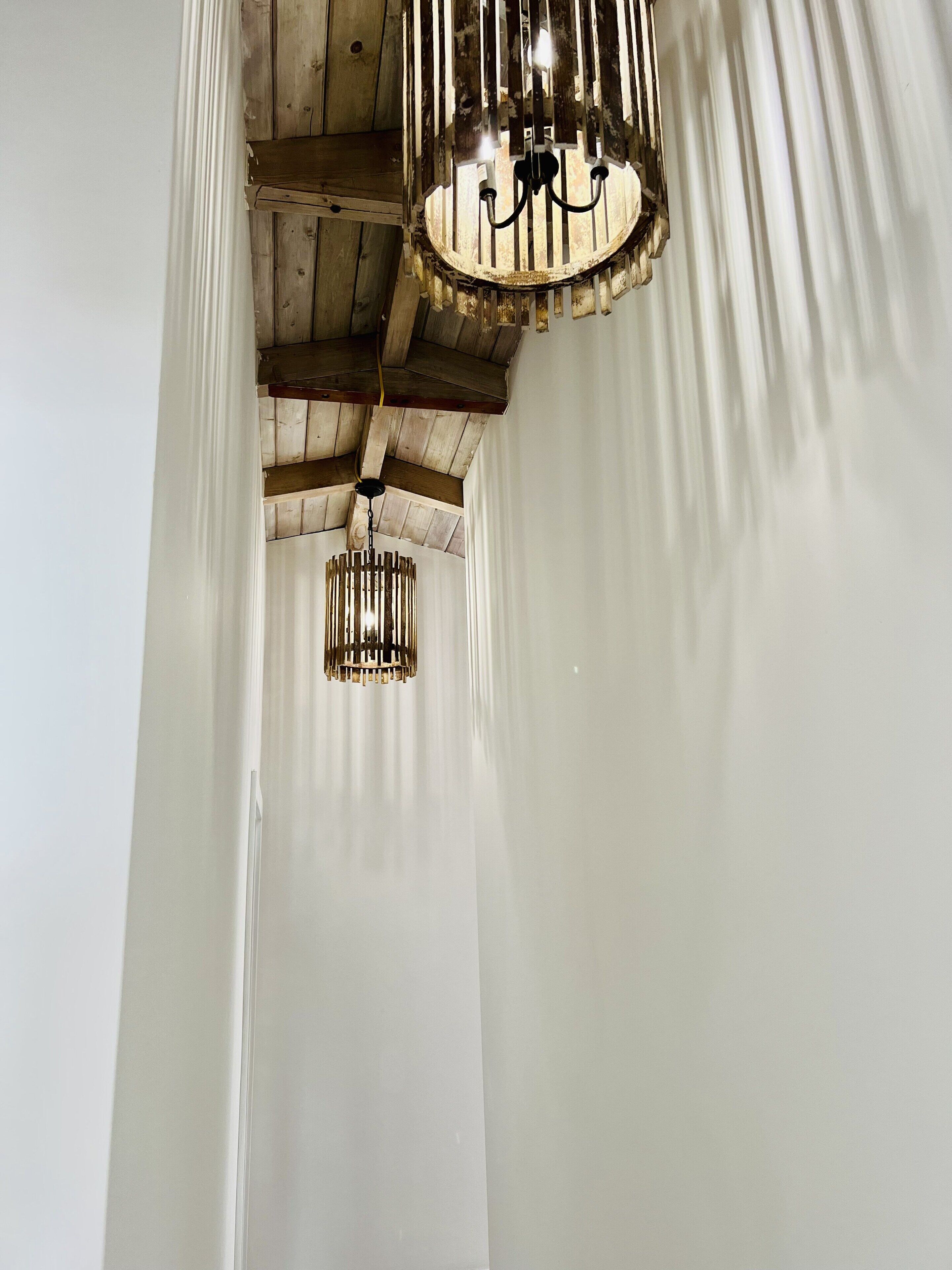 A corridor with wooden beams and two chandeliers.