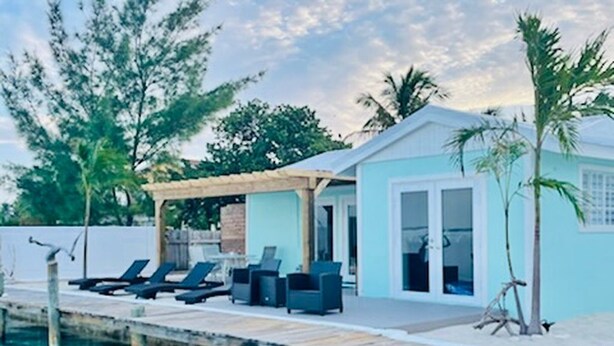 Une propriété située au bord de l’eau, dotée d’un quai, de chaises longues et d’un espace salon abrité.
