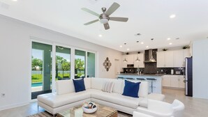 A modern living room with a sectional sofa, a glass coffee table, and a ceiling fan.