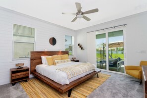 A bedroom with a large bed, a ceiling fan, and a view of the outdoors through a sliding glass door. - ✸NEW✸ 6BR, 500 steps to the beach, Private Pool, Game Room (Melbourne)