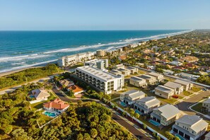 An aerial view of a coastal residential area with a large hotel featuring multiple buildings and a swimming pool. - ✸NEW✸ 6BR, 500 steps to the beach, Private Pool, Game Room (Melbourne)