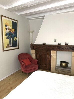A room with a fireplace, a red chair, and a painting on the wall.