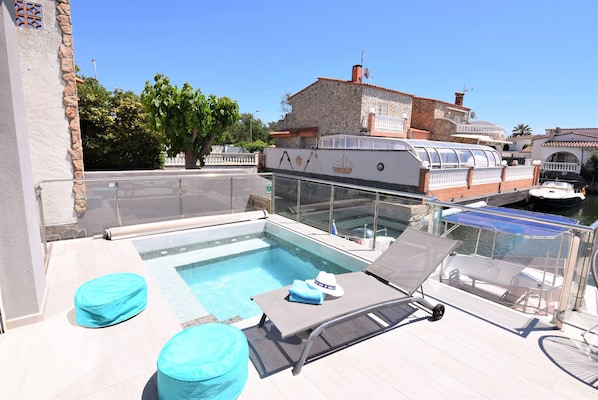Relax on the rooftop with a view of the city, featuring a small pool, lounge chairs, and ottomans.