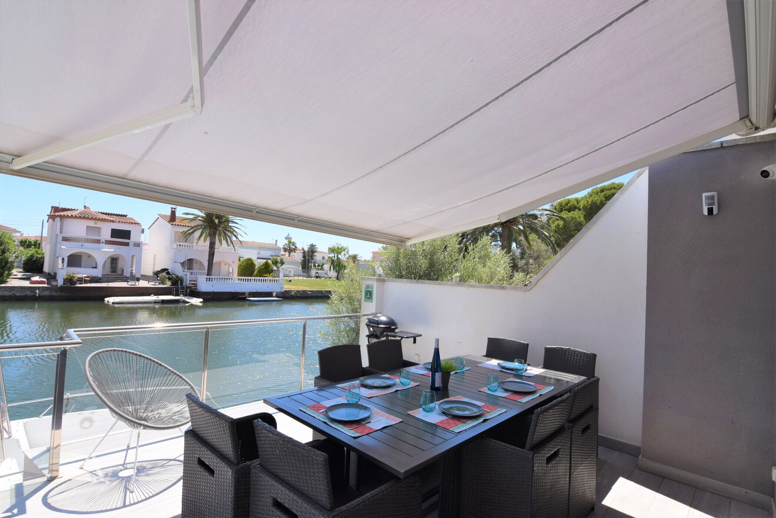 An outdoor dining area with a table set for four, overlooking a canal.