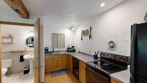 A compact kitchen with wooden cabinets, a sink, a stove, and a refrigerator. - The Incline (Norwalk)