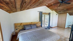 A bedroom with a wooden headboard, a large bed, a ceiling fan, and a sliding glass door leading to a balcony. - The Incline (Norwalk)
