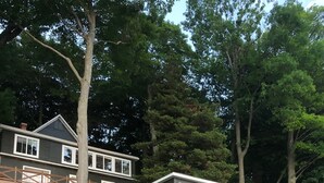 A coastal property with two cabins, one elevated on stilts, and a wooden deck connecting them.