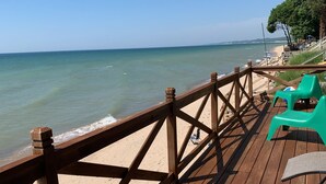A wooden deck with a railing overlooking a beach.