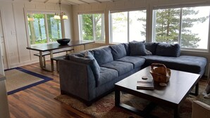 A modern living room with a sectional sofa, a coffee table, and a dining area with a bench and table.