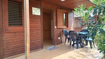 Une cabane en bois dotée d’un patio couvert comprenant une table et des chaises.