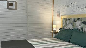 A bedroom with a bed, a nightstand, a lamp, and a wall with a floral pattern and the text "SWEET DREAMS".