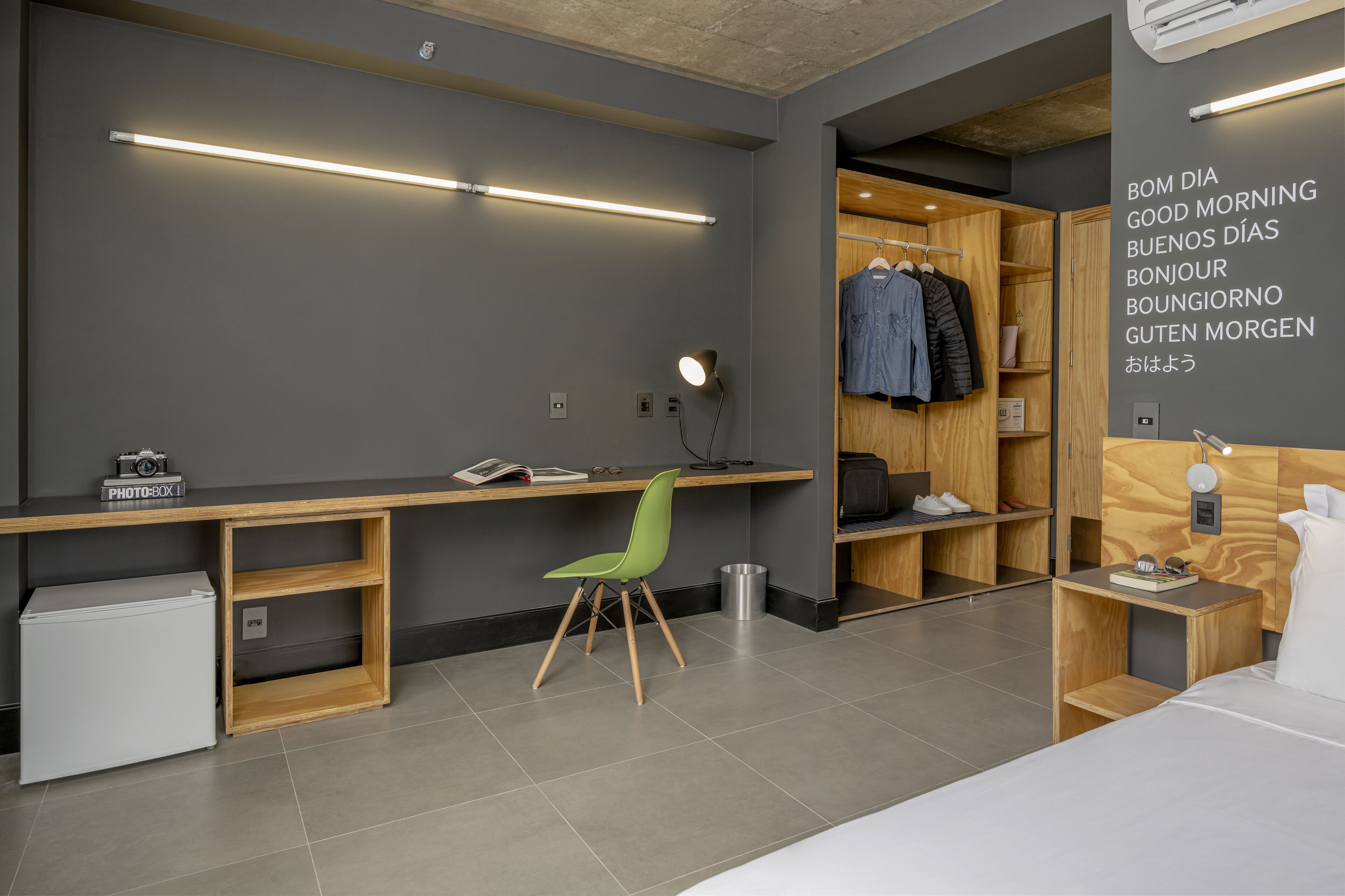 A modern hotel room with a desk, chair, and wardrobe.