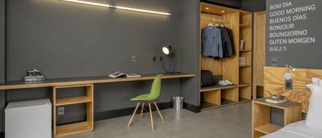 A modern hotel room with a desk, chair, and wardrobe.