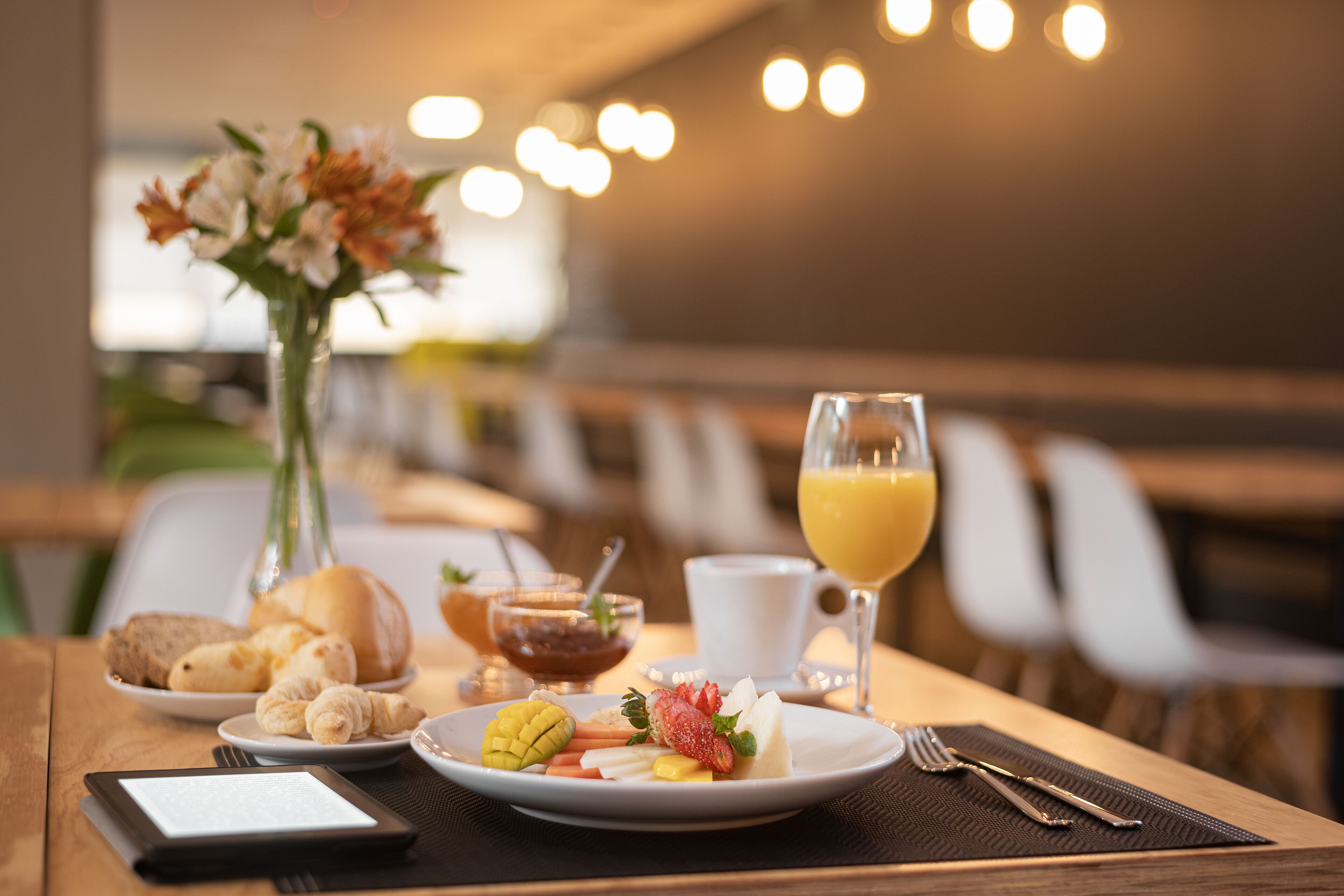 A breakfast setting with croissants, fruit, and a glass of orange juice on a wooden table.