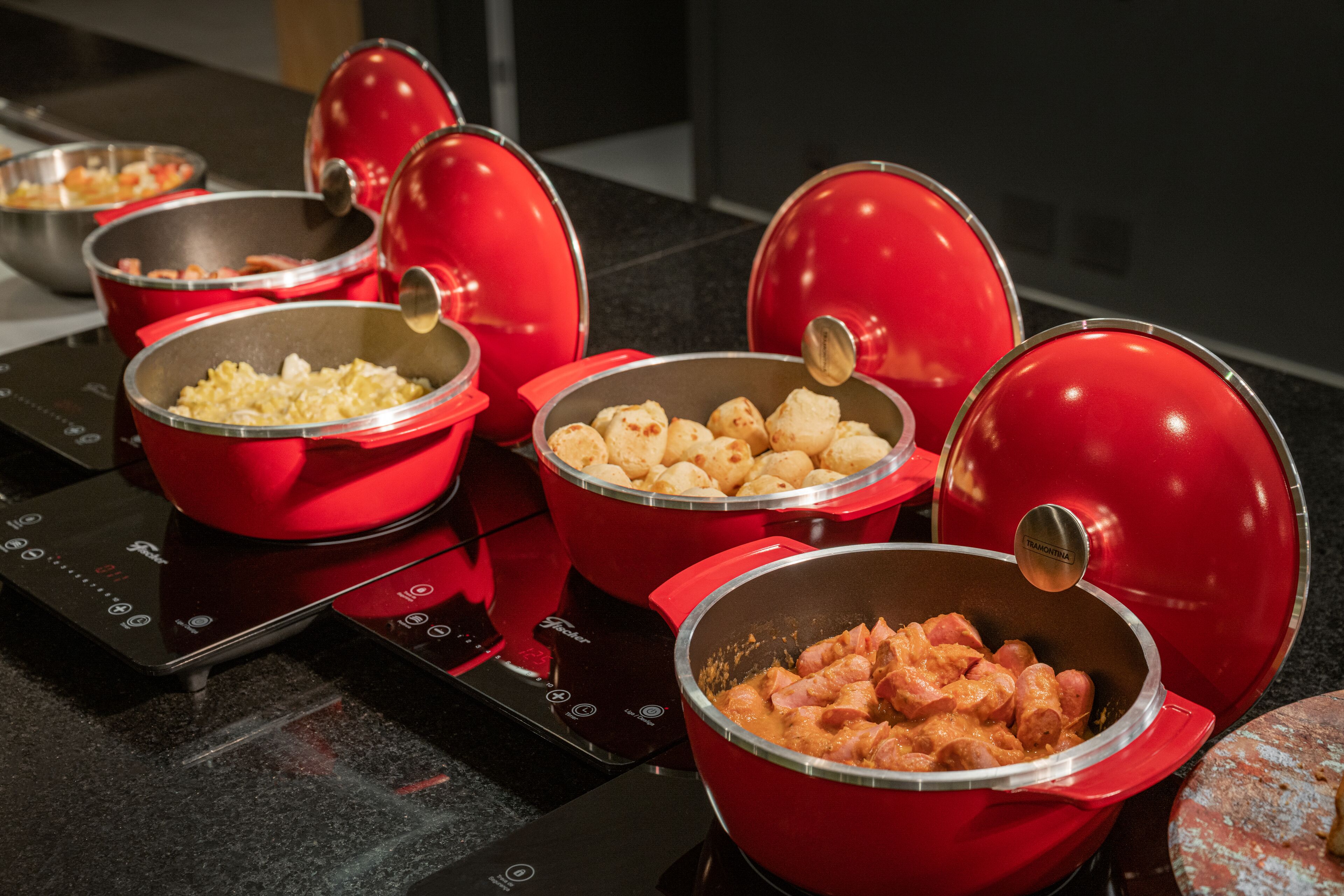 A kitchen with red pots on an induction cooktop.