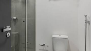 A modern bathroom with a glass-enclosed shower, a white toilet, and a towel rack.