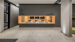 Un área de recepción moderna con suelo de mármol, una mesa de recepción y una pared que muestra saludos en varios idiomas.