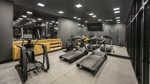 Un gimnasio con cintas de correr, elípticas y un mostrador de recepción.