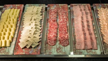 A display of various food items, including sliced meats and cheeses, arranged on metal trays.