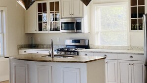 A kitchen with white cabinets, a central island, stainless steel appliances, and pendant lighting. - Reset and Relax in Luxury Cottage (Rhinebeck)