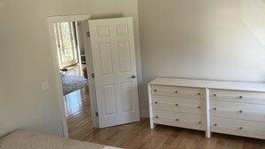 A bedroom with a bed, a dresser, and a door leading to another room. - Reset and Relax in Luxury Cottage (Rhinebeck)