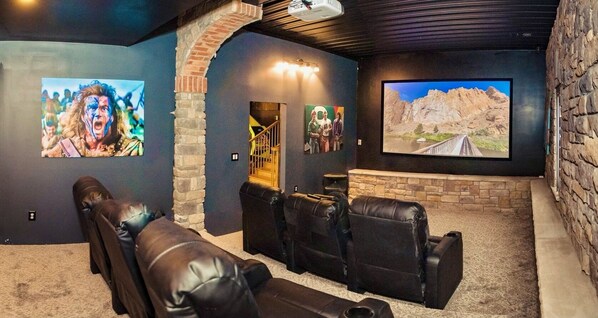 A home theater with leather recliners, a large screen, and artwork on the walls. - Pickleball, theater, game room, hot tub, & gym! (Stroudsburg)