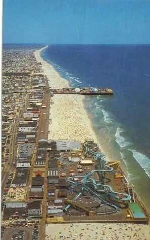 Luftaufnahme einer Küstenstadt mit Strand, einer Mole und einer Achterbahn.