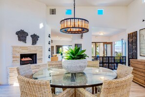 Enjoy meals in a stylish dining area with a round table, wicker chairs, and a stone fireplace.