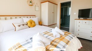 A hotel room with a bed, a wardrobe, a television, and a shower area. - The Chocolate Box (Weymouth)